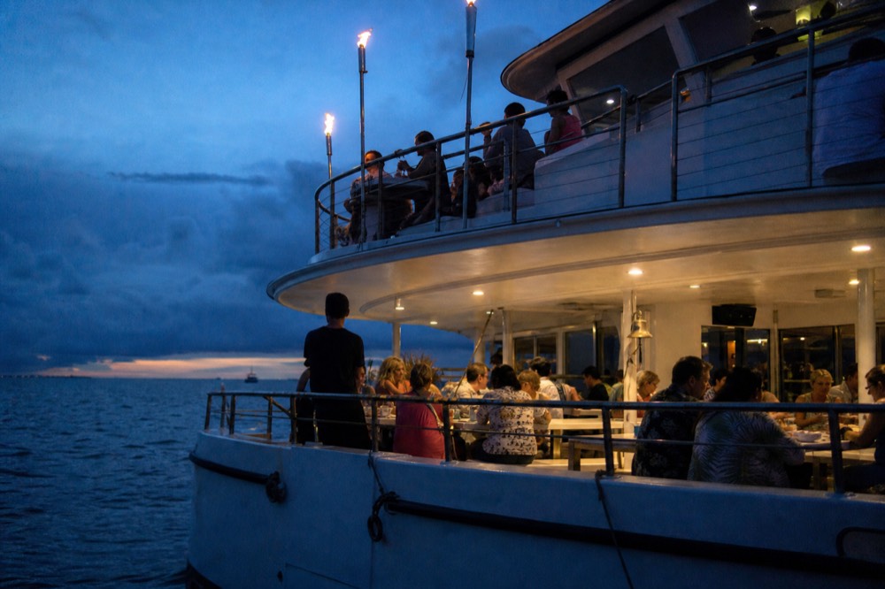 Large stable double-deck boat with families seated at long tables and children looking over the rail