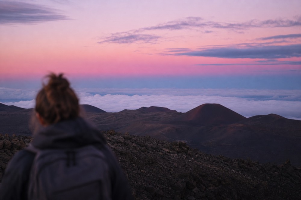 High volcanic crater rim above a flat white cloud deck at dusk with cinder cones below and no ocean visible anywhere